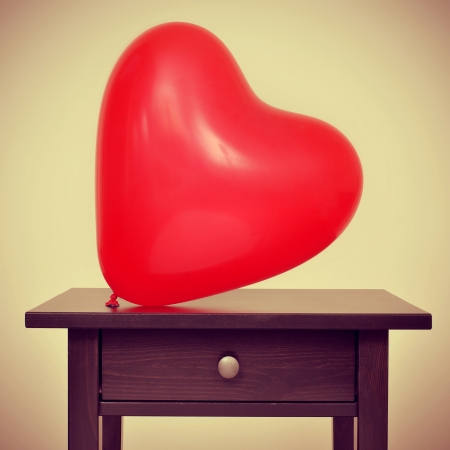 picture of a red heart-shaped balloon on a desk, with a retro effectの写真素材