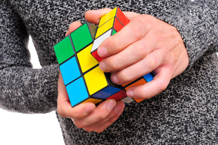 young man playing trying to solve a cube puzzleのeditorial素材