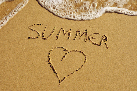 the word summer and a heart carved in the sand of a beachの写真素材