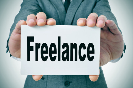 businessman showing a signboard with the word freelance written in itの写真素材