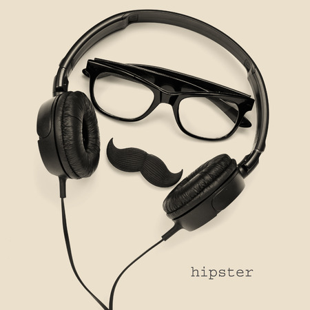 a pair of glasses, a mustache and a pair of headphones, and the word hipster on a beige backgroundの写真素材