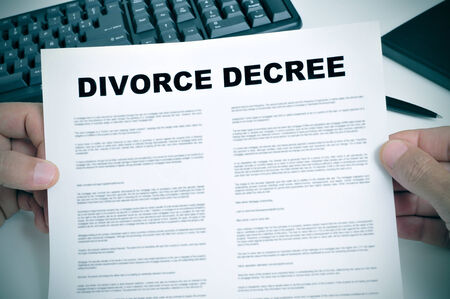 closeup of man hands holding a divorce decree on a deskの写真素材