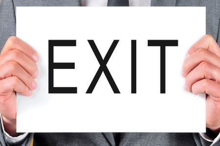 man wearing a suit holding a signboard with the word exit written in it