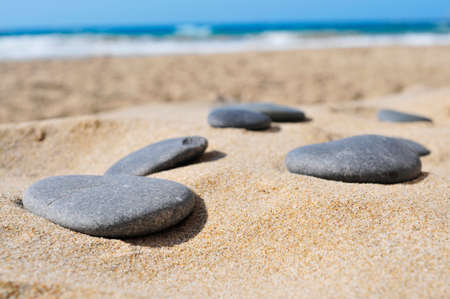 closeup of some gray flat stones on the sand of a beachの写真素材