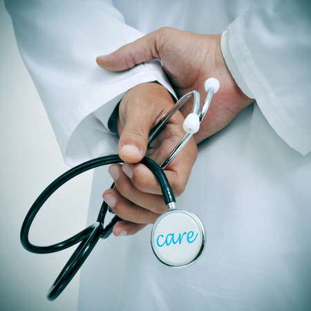 a doctor holding a stethoscope with the word care written in itの写真素材