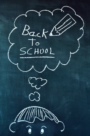 drawing of a boy with chalk in a chalkboard and a thought bubble with the text back to school written in itの写真素材
