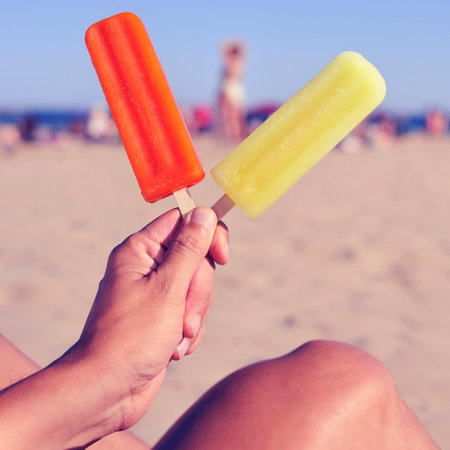 a young man with two appetizing ice pops in his hand on the beach, with a filter effect