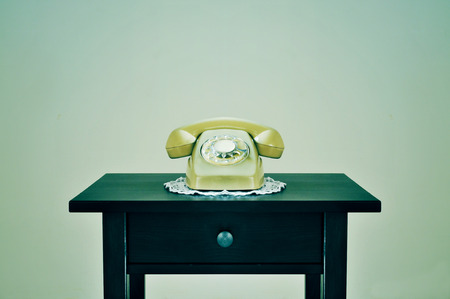 a beige old rotary dial telephone on a table, with a retro effectの写真素材