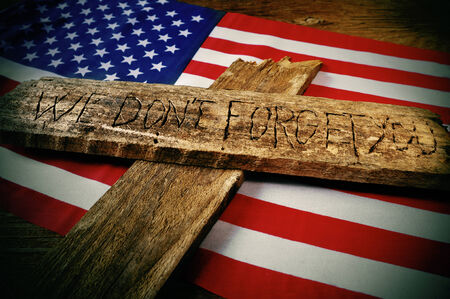 the sentence we do not forget you carved on a wooden cross over the flag of the United Statesの写真素材