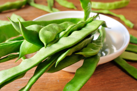 a bowl with green bean pods on a rustic wooden table