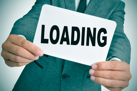 a man wearing a suit showing a signboard with the text loading written in it