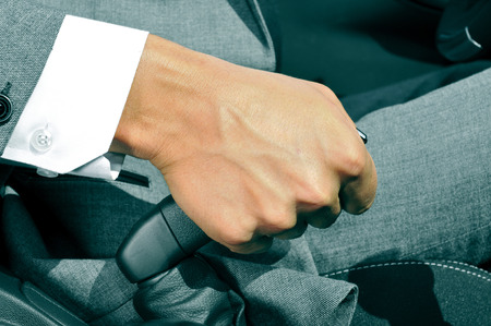closeup of a man in suit pulling the hand brake of a carの写真素材