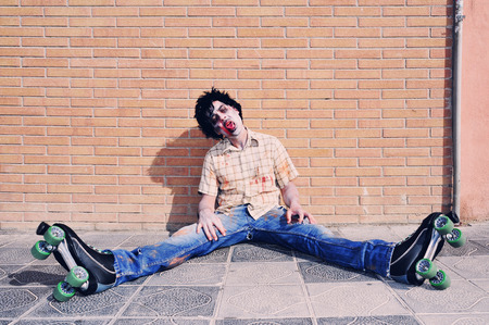 a scary zombie with roller skates sitting on the sidewalkの写真素材