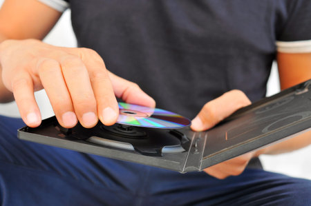 closeup of a young man pulling a DVD or a CD out of its case