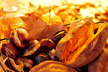 some roasted chestnuts and sweet potatoes in a basket with autumn leavesの写真素材