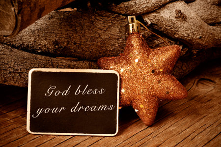 the text god bless your dreams written in a blackboard and a christmas star and a pile of logs in...