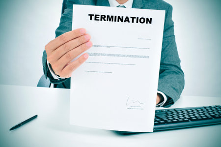 a man in suit in his desk showing a figured signed termination document