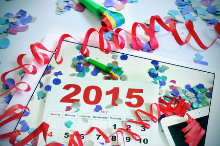 a tablet with a picture of a 2015 calendar on an office desk full of confetti, streamers and a party...