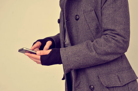 a young man in coat wearing gloves using a smartphone