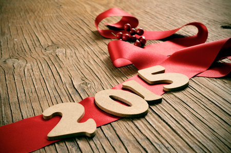 wooden numbers forming 2015, as the new year, and a red satin ribbon on a rustic wooden table