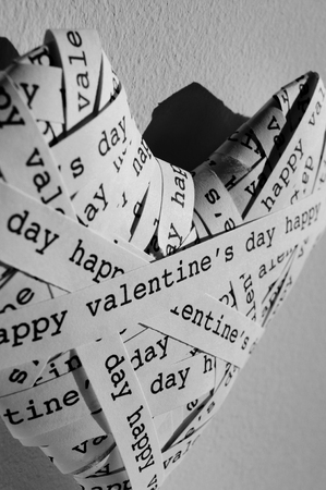 closeup of a heart made with paper strips with the text happy valentines written in it in black and whiteの写真素材