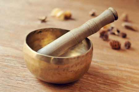closeup of a tibetan singing bowl with its mallet on a table with dried flowersの写真素材