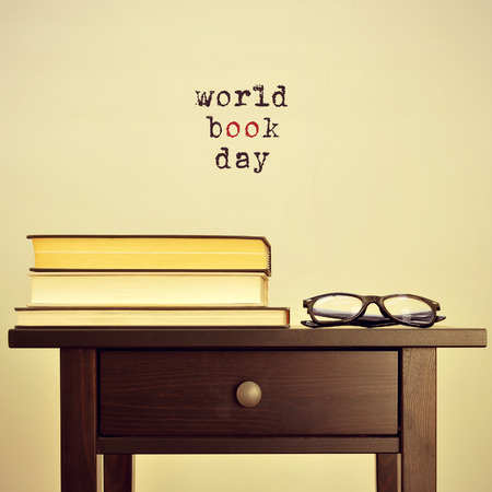 black eyeglasses and some books on a table and the sentence world book day on a beige background, with a retro effectの写真素材