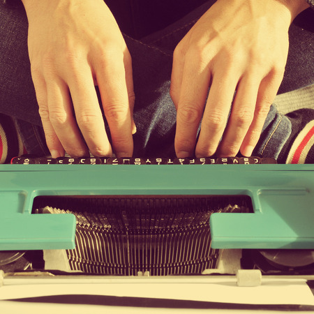 a young man typing in an old typewriter on the bed, with a retro effectの写真素材