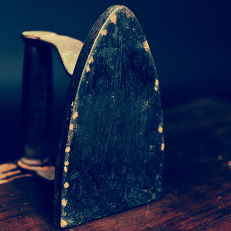closeup of an old flatiron on a wooden table, with a filter effectの写真素材