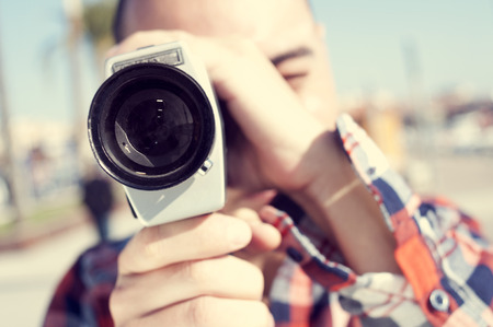 a young man with a plaid shirt filming with a Super 8 camera outdoorsの写真素材