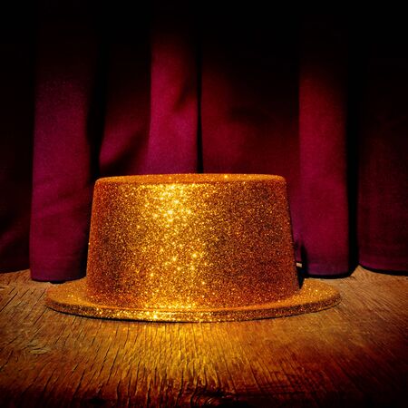 a golden top hat on a stage with the theater curtain in the backgroundの写真素材