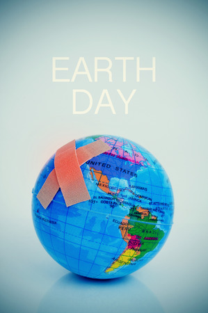 Two adhesive bandages forming a cross on a terrestrial globe and the text earth dayの写真素材