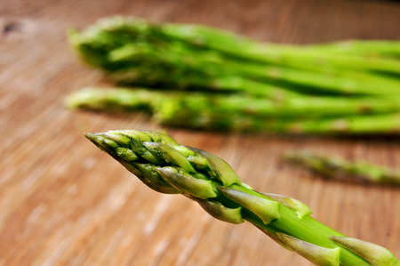 closeup of some raw asparagus on a rustic wooden tableの写真素材