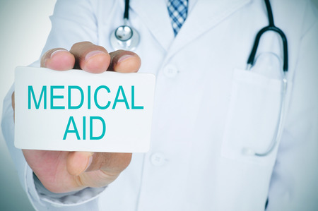 a young caucasian doctor shows a signboard with the text medical aidの写真素材
