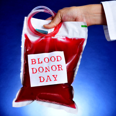 closeup of the hand of a doctor holding a blood bag with a sticker with the text blood donor dayの写真素材