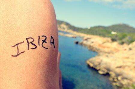 closeup of the arm of a young man with the word Ibiza written in it, in the southern coast of Ibiza Island, in Spain, in the Mediterranean seaの写真素材