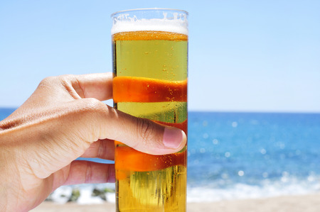 closeup of a young caucasian man having a refreshing beer on the beachの写真素材