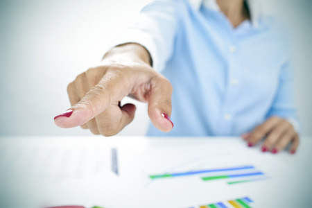 closeup of a businesswoman sitting at her desk, full of charts, pointing with her finger the way outの写真素材
