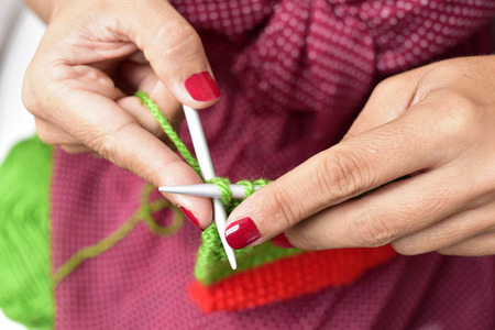 closeup of a young woman hand knitting with green yarnの写真素材