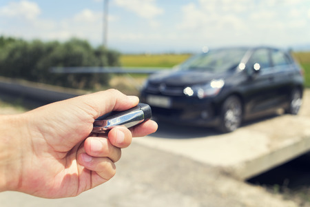 closeup of a young man unlocking the doors of his car with the control remote key, outdoors, with a filter effectの写真素材
