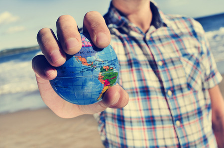 closeup of a young caucasian man with a world globe in his handの写真素材