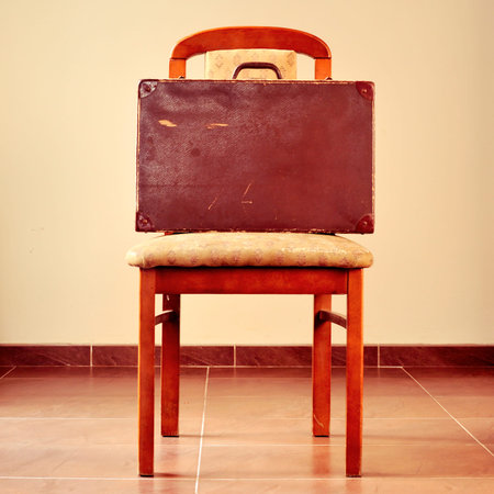 an old brown suitcase on a worn and retro chairの写真素材