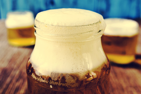 refreshing beer served in glass jars on a rustic wooden tableの写真素材