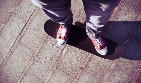 self-portrait of a young man wearing red sneakers on a skate boardの写真素材