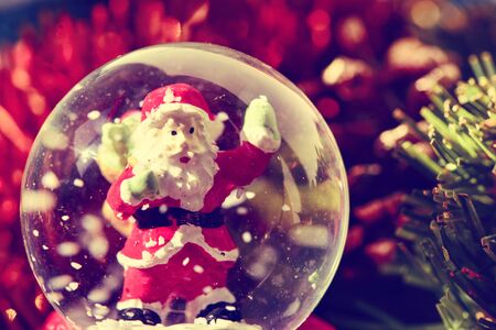 closeup of a christmas snow globe with a santa claus in it and some other christmas ornamentsの写真素材