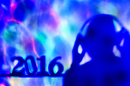 colorful lights projected on the number 2016, as the new year, and a disc jockey man wearing...