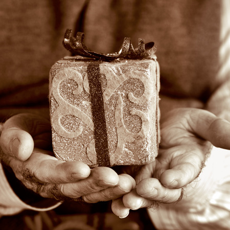 closeup of an old caucasian man with a gift in his hands, in sepia toningの写真素材