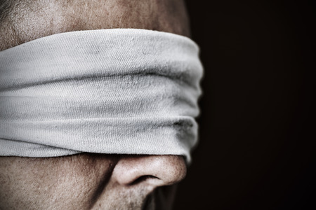 closeup of a young man with a blindfold in his eyes, as a symbol of oppression or repression, with a dramatic effectの写真素材