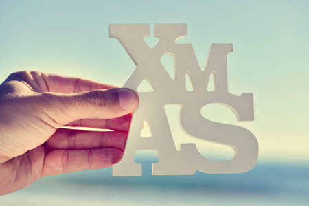 closeup of a young caucasian man holding the three-dimensional word xmas in his hands, with the...