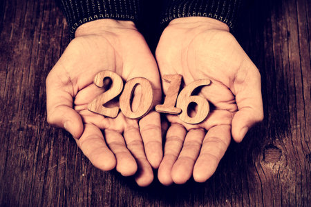 closeup of wooden numbers forming the number 2016, as the new year, in the hands of a man, against a...